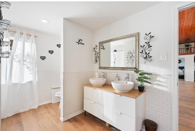 bathroom with tile walls, vanity, hardwood / wood-style flooring, and a healthy amount of sunlight