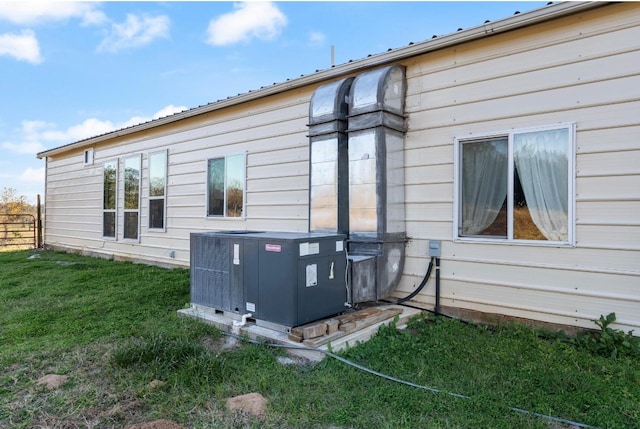 view of side of home featuring a lawn and central air condition unit