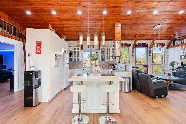 kitchen featuring a breakfast bar area, pendant lighting, tasteful backsplash, light wood-type flooring, and white cabinets