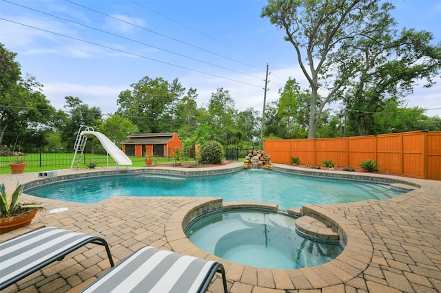 view of pool with a water slide, a patio area, and an in ground hot tub