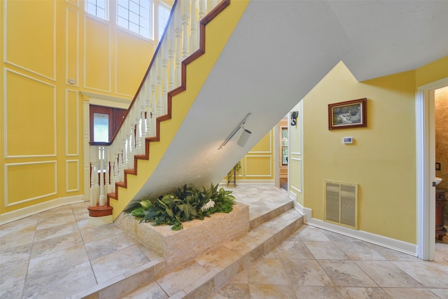 staircase with a towering ceiling and plenty of natural light