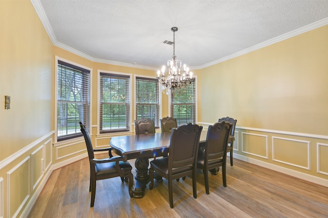 dining room featuring hardwood / wood-style floors, an inviting chandelier, crown molding, and a textured ceiling