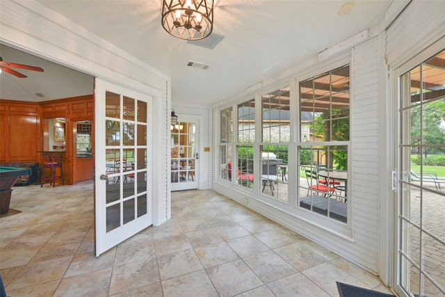 unfurnished sunroom with ceiling fan with notable chandelier, billiards, and french doors