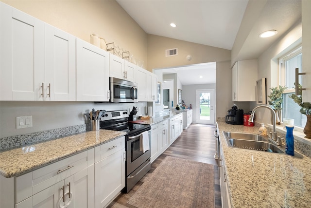 kitchen featuring vaulted ceiling, sink, appliances with stainless steel finishes, and white cabinetry