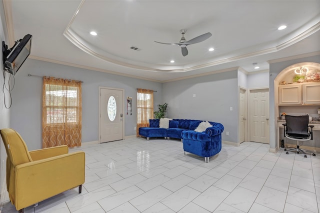 living room with a tray ceiling, crown molding, and ceiling fan