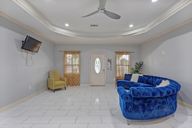 sitting room with a raised ceiling, ceiling fan, and ornamental molding