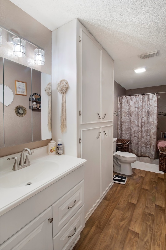 bathroom with vanity, toilet, hardwood / wood-style flooring, and a textured ceiling