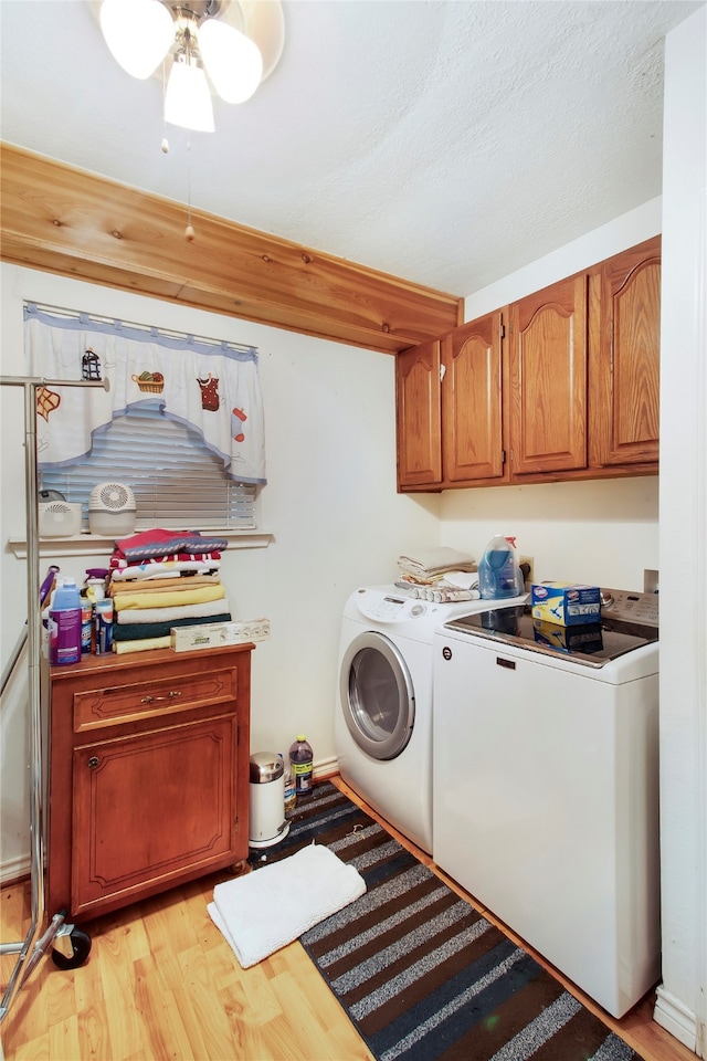 laundry room with washing machine and dryer, light hardwood / wood-style flooring, ceiling fan, cabinets, and a textured ceiling