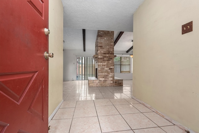 hallway featuring vaulted ceiling with beams, light tile patterned floors, a textured ceiling, and ornate columns