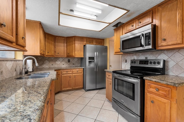 kitchen featuring backsplash, light tile patterned floors, sink, and appliances with stainless steel finishes