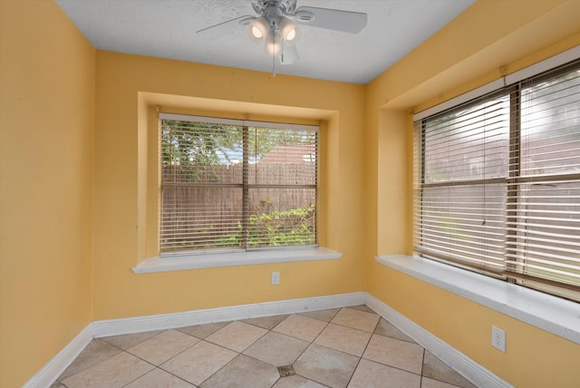 tiled empty room with a textured ceiling and ceiling fan