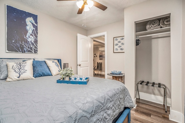 bedroom with dark wood-type flooring, a textured ceiling, ceiling fan, and a closet