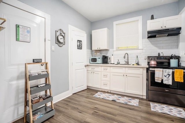 kitchen featuring stainless steel electric range, sink, white cabinets, and light hardwood / wood-style floors