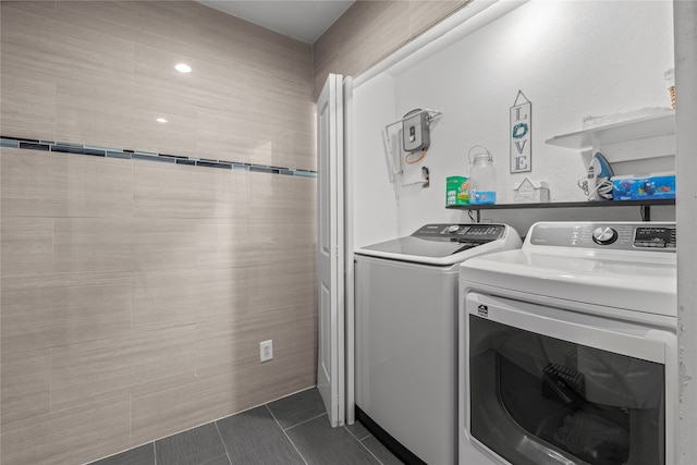 clothes washing area with washing machine and dryer and dark tile patterned floors