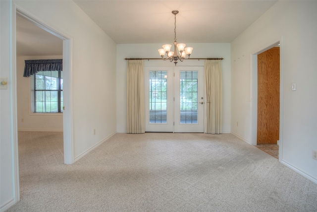 empty room featuring light carpet and a notable chandelier