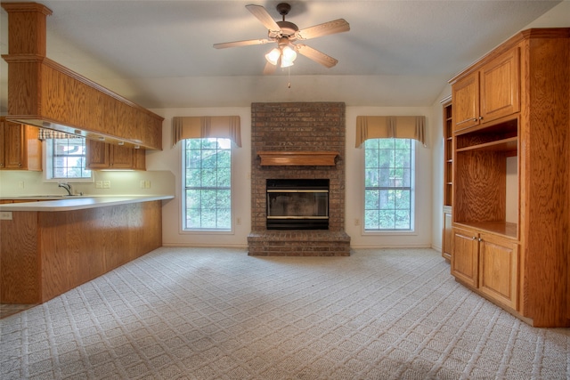 kitchen with ceiling fan, kitchen peninsula, a fireplace, and light carpet