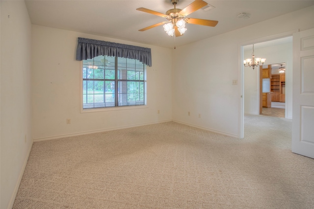 carpeted empty room featuring ceiling fan with notable chandelier