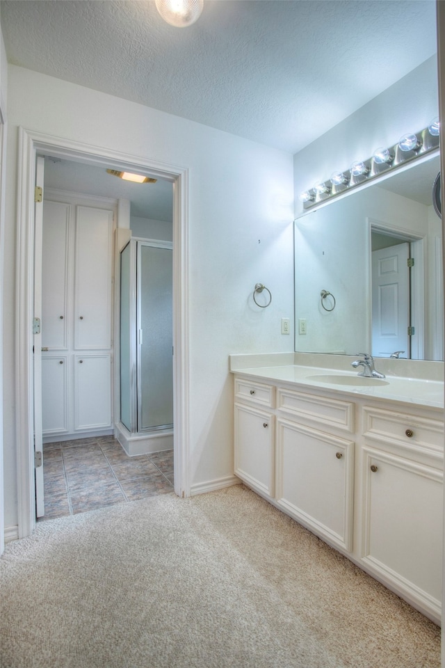 bathroom featuring a shower with door, vanity, tile patterned floors, and a textured ceiling