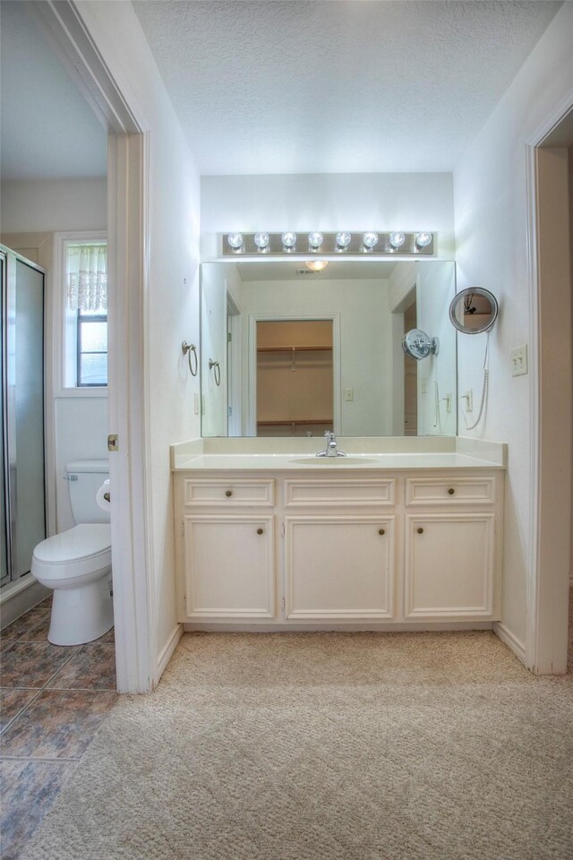 bathroom with an enclosed shower, toilet, a textured ceiling, and vanity