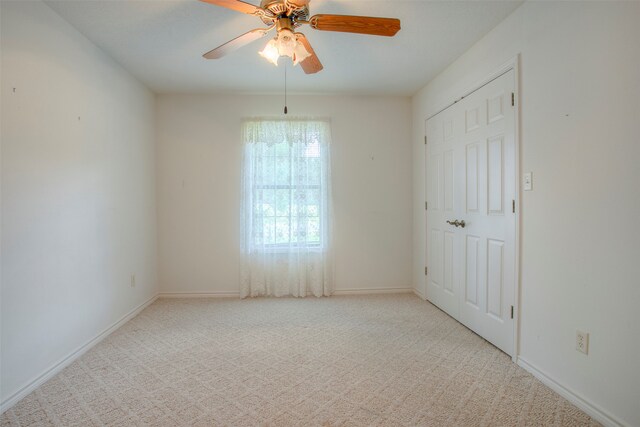 empty room with ceiling fan and light carpet