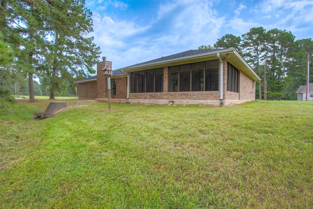 rear view of house featuring a sunroom and a yard