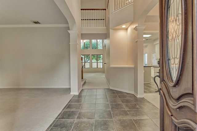 entryway with ornate columns, a towering ceiling, and ornamental molding