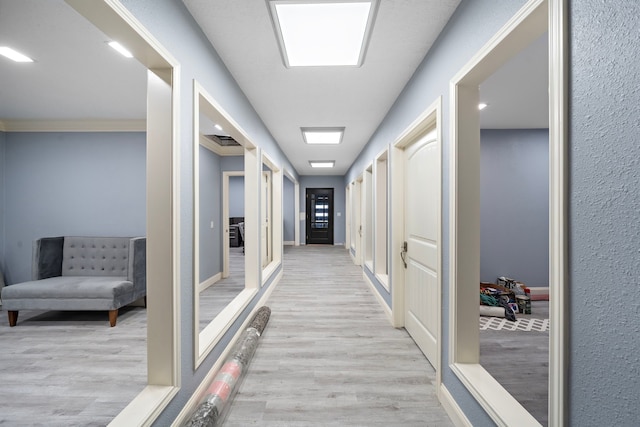 hall with ornamental molding and light hardwood / wood-style flooring