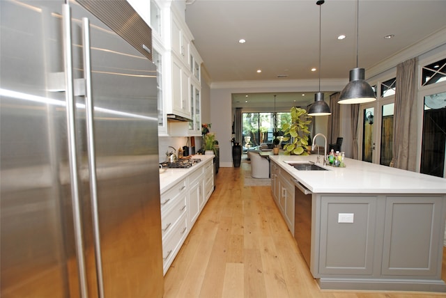 kitchen featuring light wood-type flooring, white cabinetry, stainless steel appliances, sink, and a center island with sink