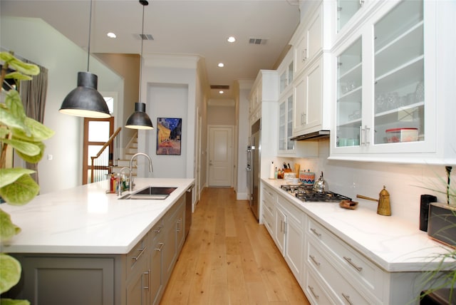 kitchen with light wood-type flooring, a kitchen island with sink, white cabinetry, light stone counters, and sink