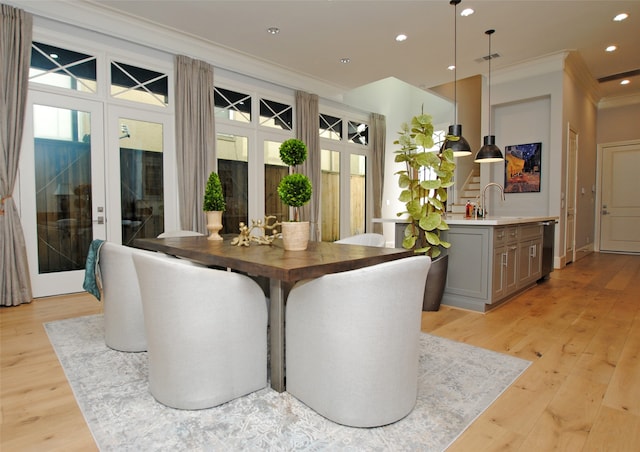 dining room with a wealth of natural light, ornamental molding, light hardwood / wood-style floors, and french doors