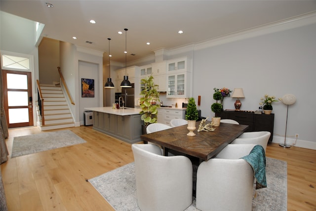 dining space with ornamental molding, light hardwood / wood-style flooring, and sink