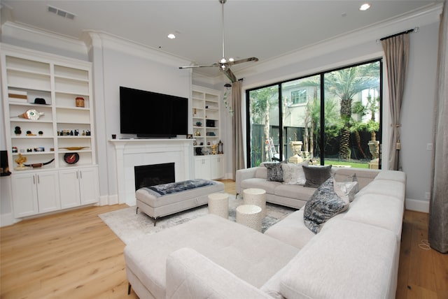 living room featuring ornamental molding, a wealth of natural light, light hardwood / wood-style flooring, and built in shelves