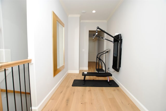 exercise room with ornamental molding and light hardwood / wood-style flooring