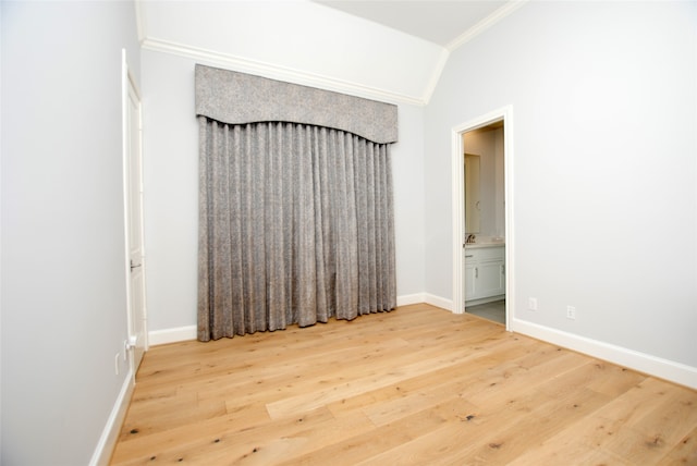 unfurnished room featuring light wood-type flooring, crown molding, and vaulted ceiling