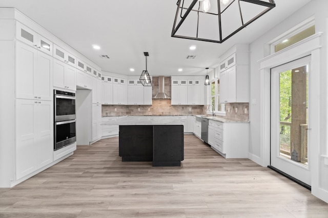 kitchen featuring a kitchen island, decorative light fixtures, wall chimney exhaust hood, appliances with stainless steel finishes, and decorative backsplash