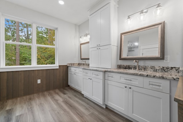 bathroom featuring hardwood / wood-style flooring, wooden walls, and vanity