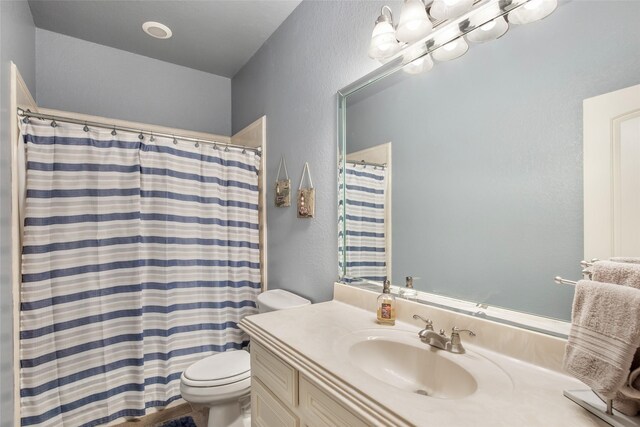 bathroom featuring a shower with shower curtain, vanity, and toilet