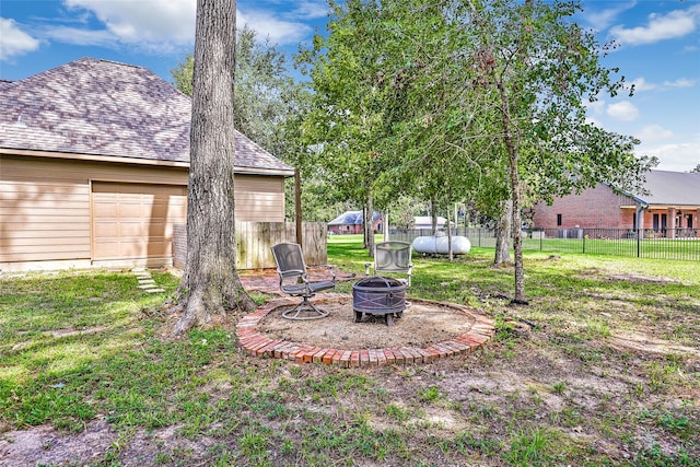 view of yard featuring a garage and an outdoor fire pit