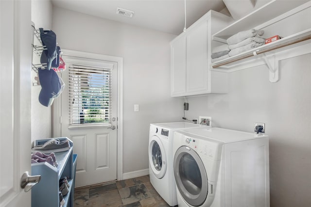 clothes washing area featuring cabinets and separate washer and dryer