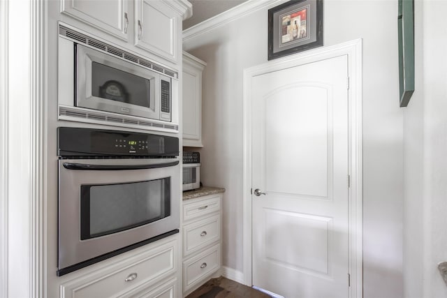 kitchen featuring white cabinets, light stone countertops, ornamental molding, and stainless steel appliances