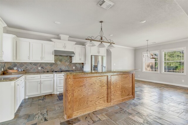 kitchen with backsplash, stainless steel fridge with ice dispenser, a kitchen island, white cabinetry, and extractor fan