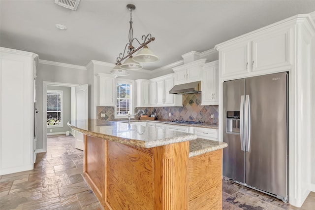 kitchen featuring light stone counters, stainless steel appliances, exhaust hood, decorative light fixtures, and white cabinetry