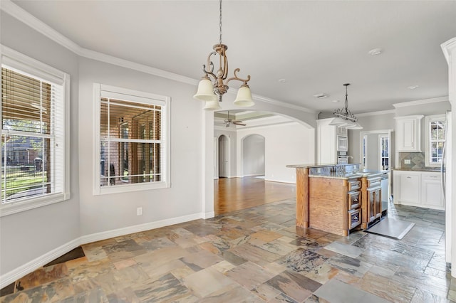 kitchen featuring white cabinetry, light stone counters, pendant lighting, a center island with sink, and ceiling fan with notable chandelier