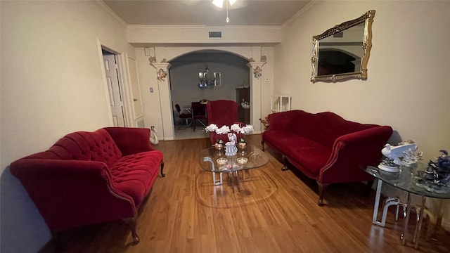 living room featuring crown molding, ceiling fan with notable chandelier, and wood-type flooring