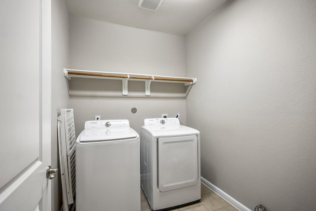 washroom with light tile patterned floors, laundry area, visible vents, baseboards, and washer and clothes dryer