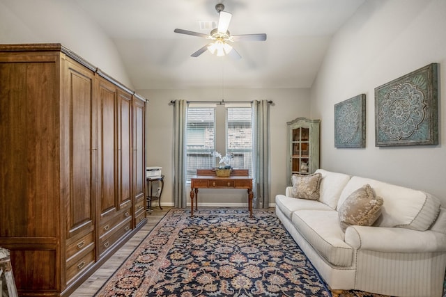 living area featuring light wood-style floors, ceiling fan, baseboards, and vaulted ceiling