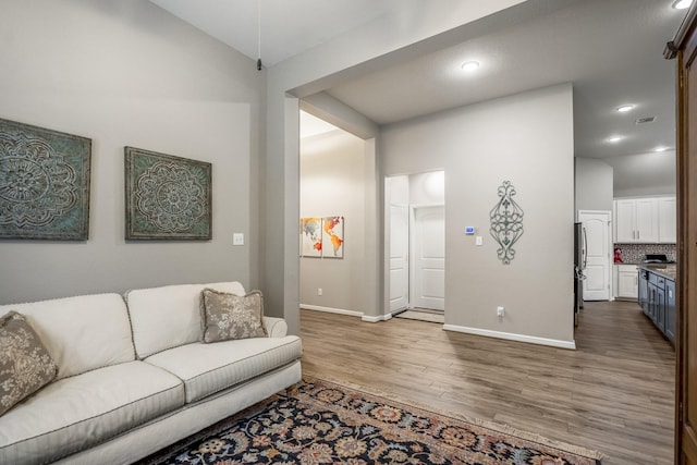 living room with lofted ceiling, recessed lighting, wood finished floors, visible vents, and baseboards