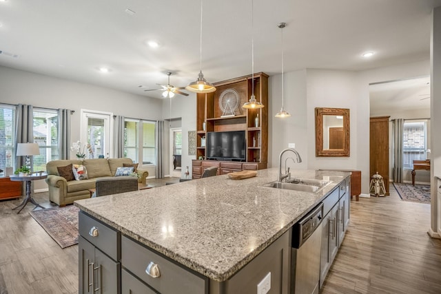 kitchen with a kitchen island with sink, gray cabinetry, wood finished floors, a sink, and dishwasher