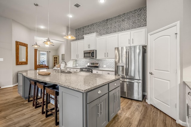 kitchen featuring visible vents, appliances with stainless steel finishes, gray cabinetry, white cabinetry, and a sink