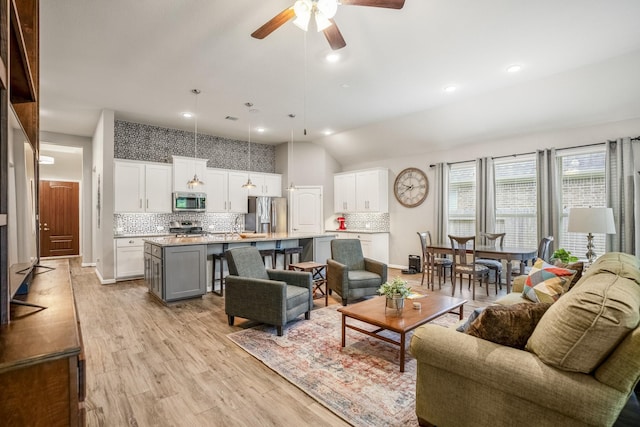 living room featuring baseboards, recessed lighting, a ceiling fan, and light wood-style floors